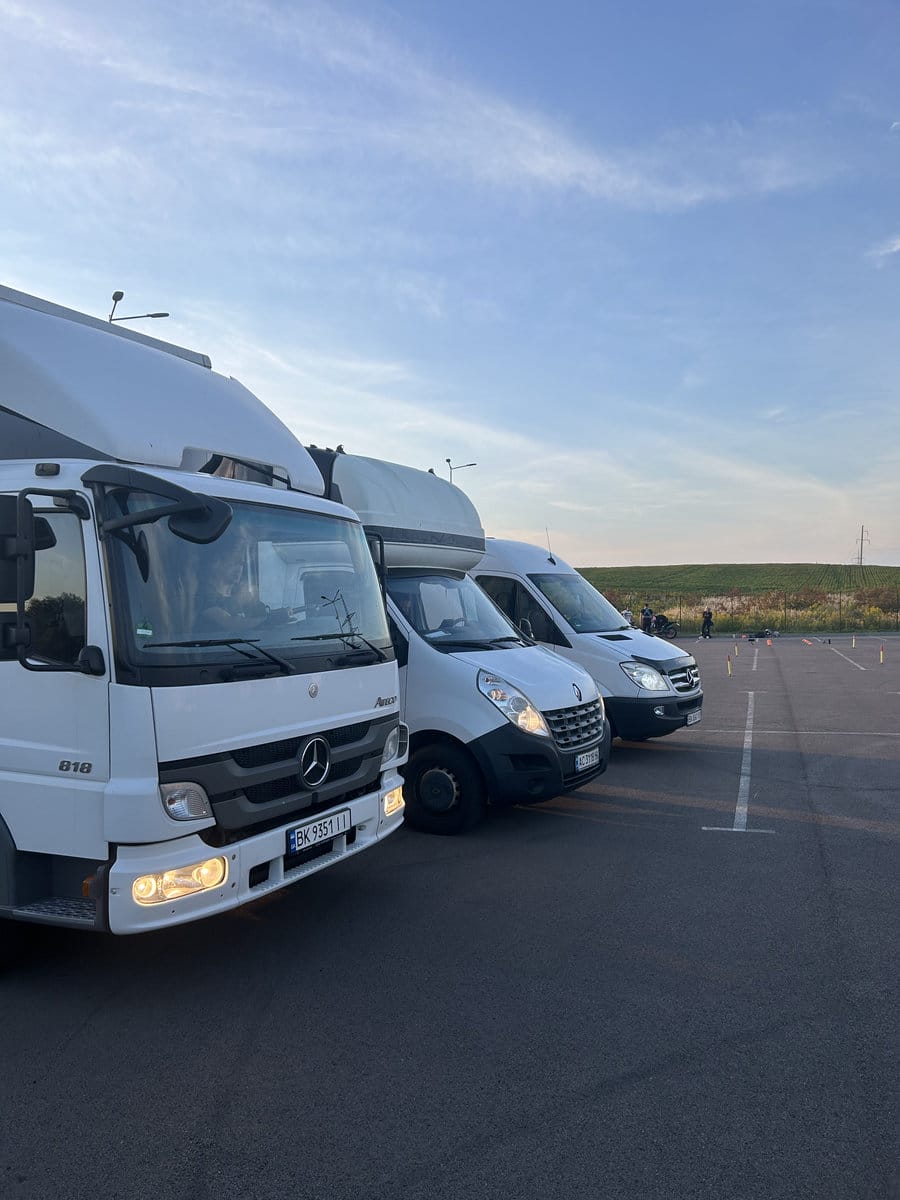 Міжміський переїзд Три вантажних автомобіля з увімкненими фарами, підготовлені до міжміського переїзду по Україні