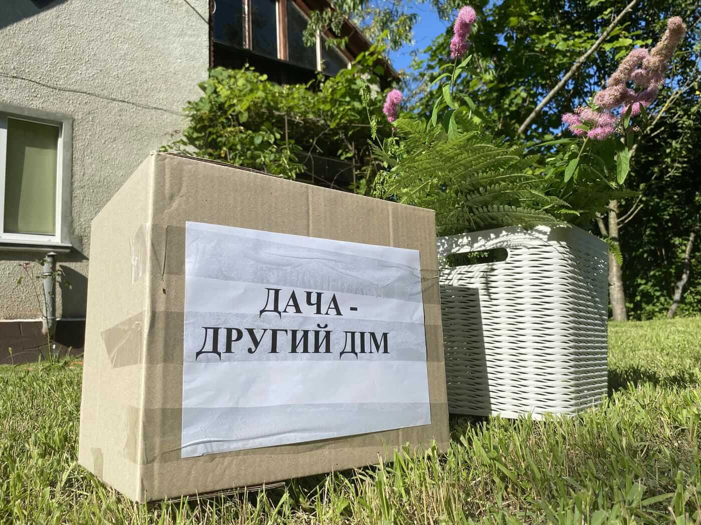 Організація дачного переїзду: коробка з написом «Дача — другий дім» на фоні заміського будинку.